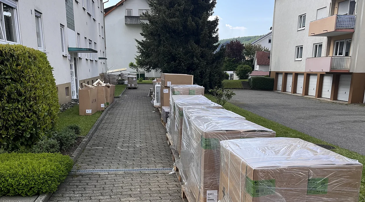 Verpackte Speicheröfen auf einem Fußweg vor einem Mehrfamilienhaus