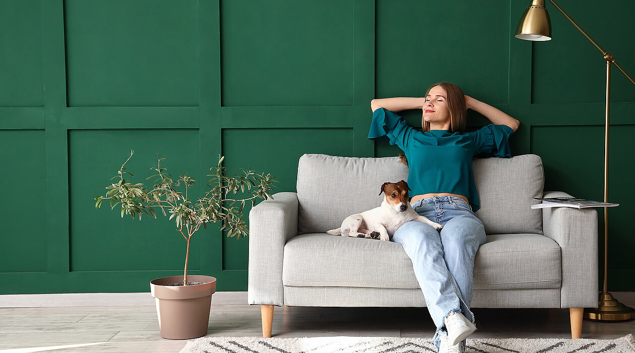 Eine entspannte Frau mit Hund auf einem Sofa