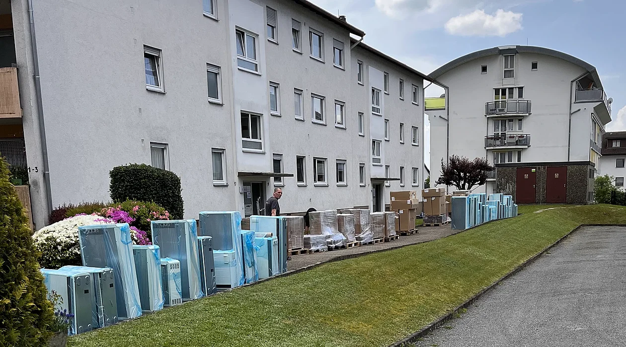 Anlieferung von Speicheröfen vor einem Mehrfamilienhaus